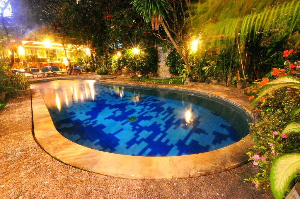 a large swimming pool in a yard at night at Swastika Guesthouse Sanur in Sanur