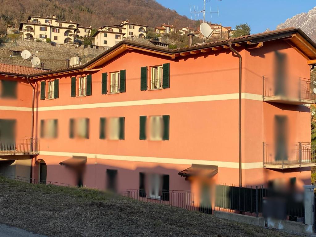 an orange building on a hill with houses in the background at River House in Porlezza