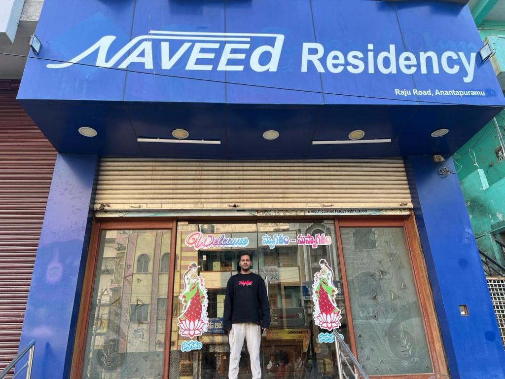 un hombre parado frente a una tienda de residencia ondeada en Naveed Residency en Anantapur