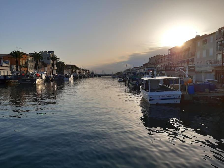 un bateau est amarré dans un canal avec des bâtiments dans l'établissement Appartement avec accès piscine, proximité mer, au Grau-du-Roi