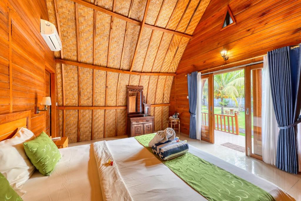 a bedroom with a large bed in a room with wooden walls at Puri Garden Penida in Nusa Penida