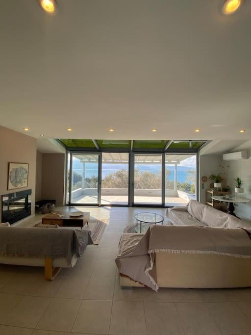 a large living room with couches and tables and windows at Aegean Blue Villa in Mytilene