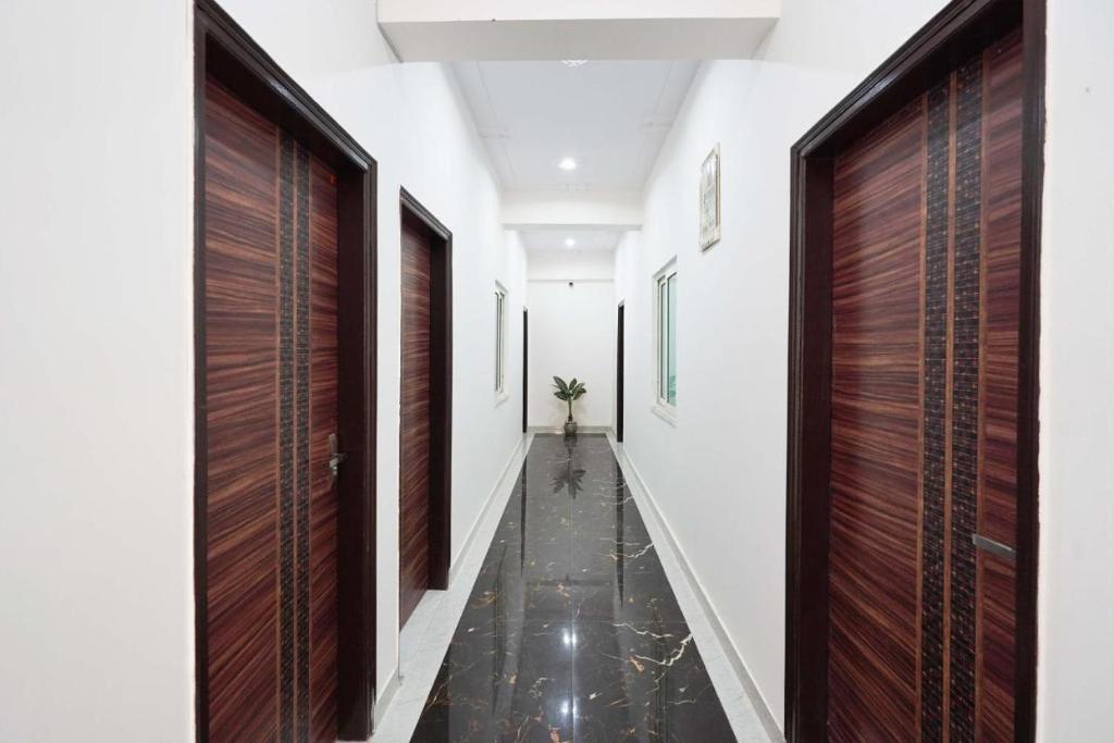 a hallway with wooden doors and a floor with black tiles at Marut Hotel in Noida