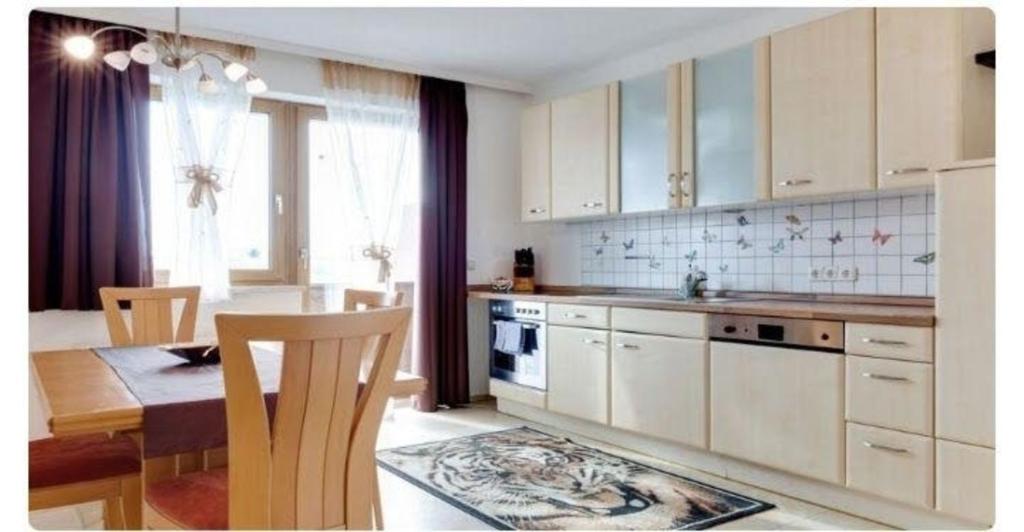 a kitchen with white cabinets and a table and a dining room at Ferienwohnung in Ulrichsberg in Ulrichsberg
