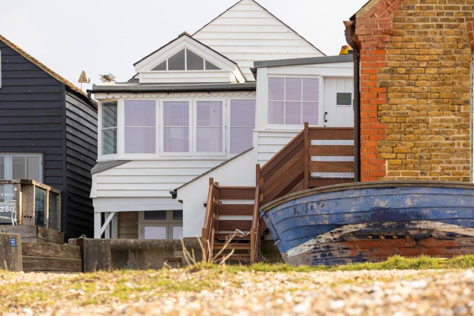 a white house with a blue boat in front of it at Stag Cottage, Sea wall in Whitstable