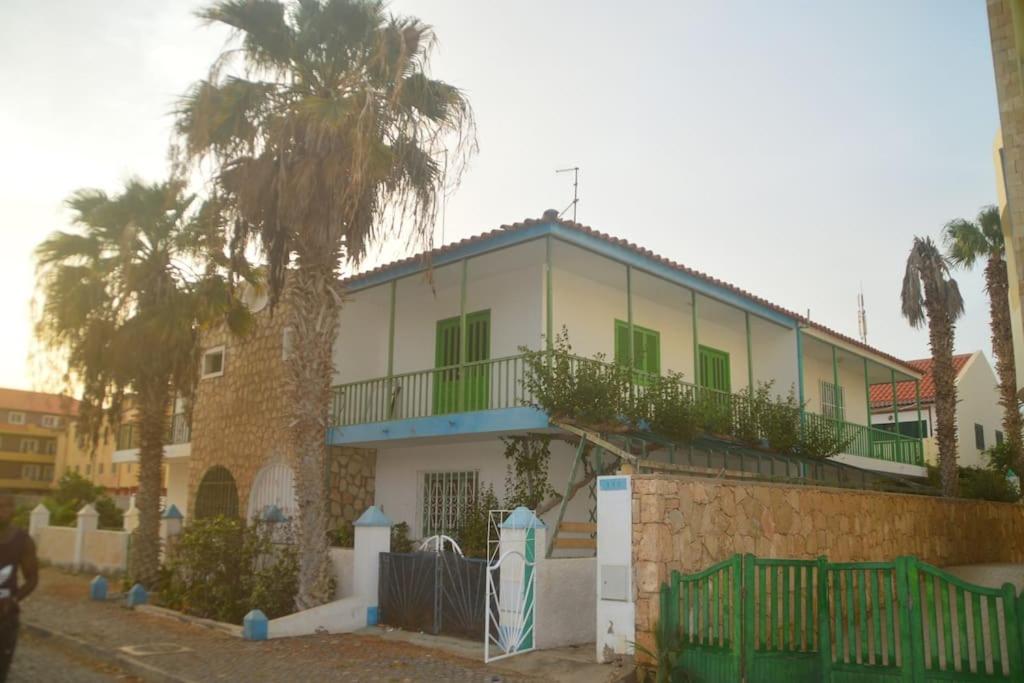 a white house with green windows and palm trees at Private surf house & garden, v near beach & town in Santa Maria