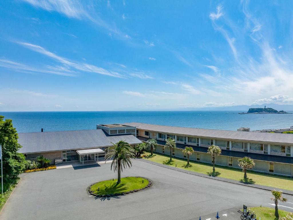 un edificio de oficinas con una palmera frente al océano en Kamakura Prince Hotel, en Kamakura