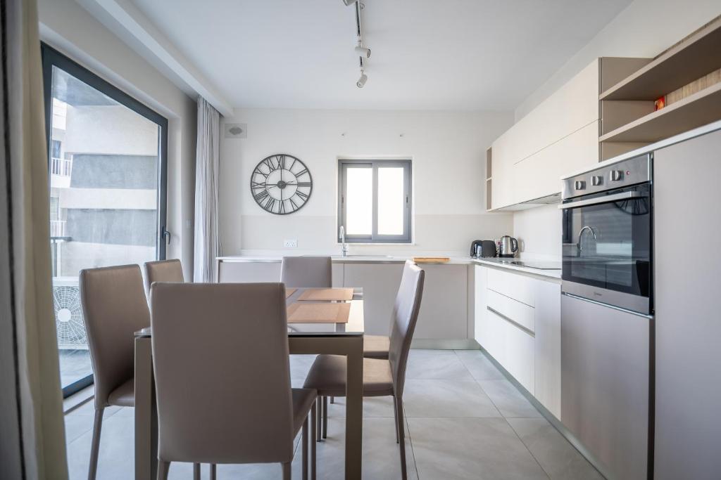 a kitchen and dining room with a table and chairs at Seabreeze Luxury Apartment in St Paul's Bay