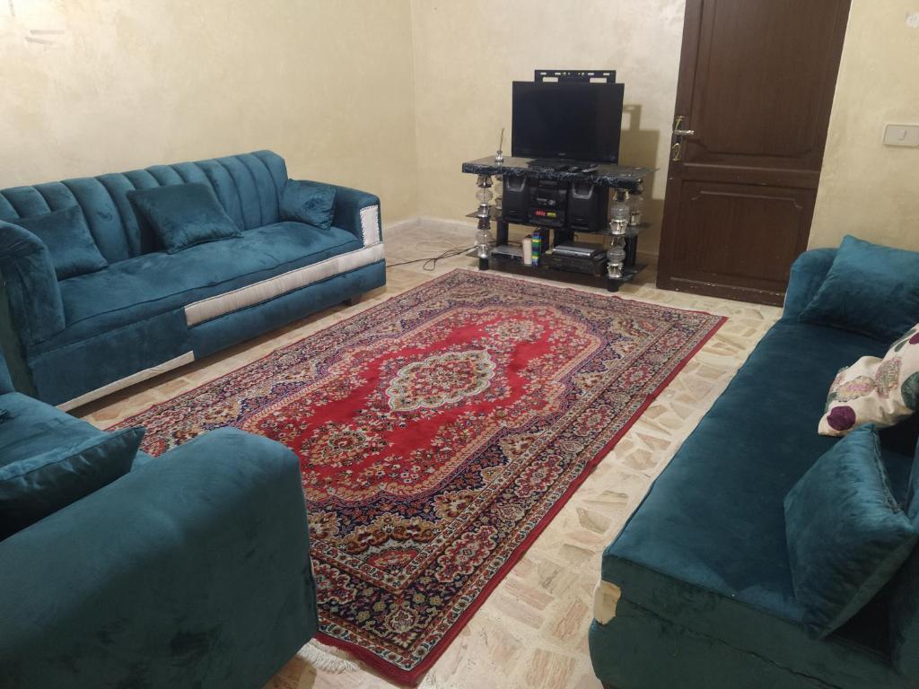 a living room with two blue couches and a rug at Furnished apartment for rent in Amman