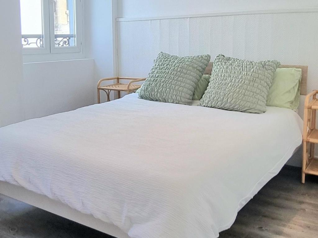 - un lit blanc avec des oreillers verts au-dessus dans l'établissement Golden Mont Centre Appartement, à Pau