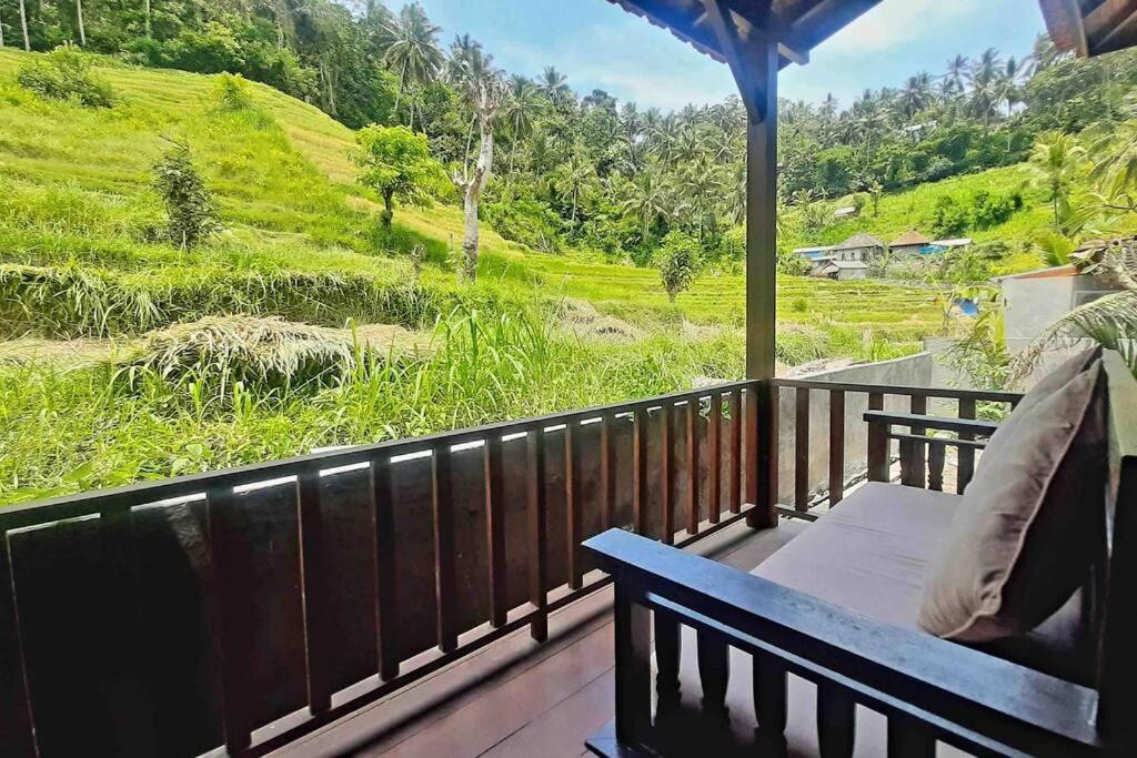 een veranda met een bank en uitzicht op een heuvel bij Umaduran Wooden Hut in Silebeng