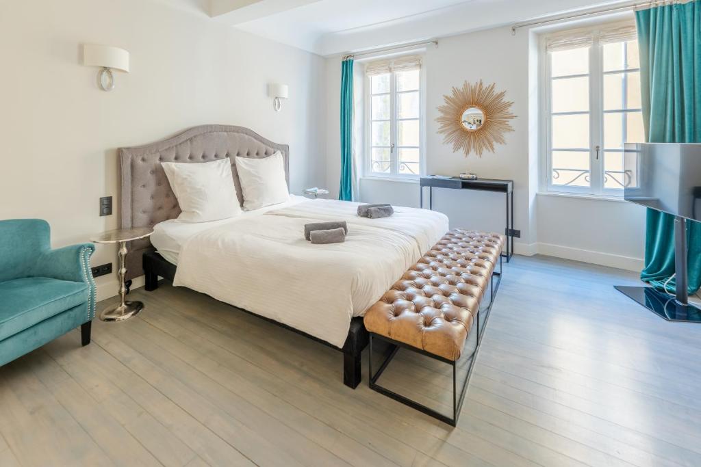 - une chambre avec un grand lit et une chaise bleue dans l'établissement Beau Clocher, à Saint-Tropez