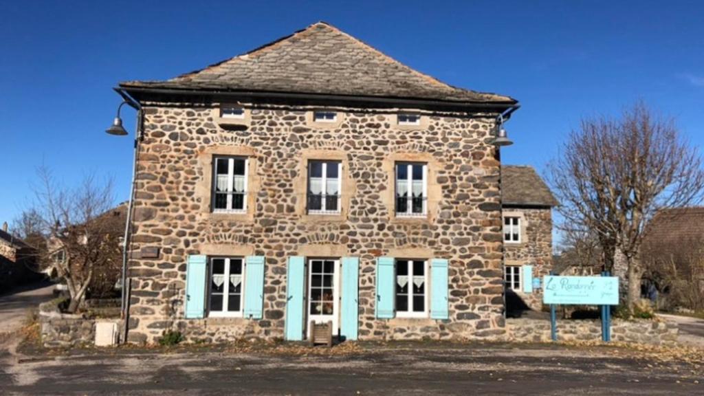 un antiguo edificio de piedra con puertas y ventanas azules en Gite La Randonnée en Moudeyres