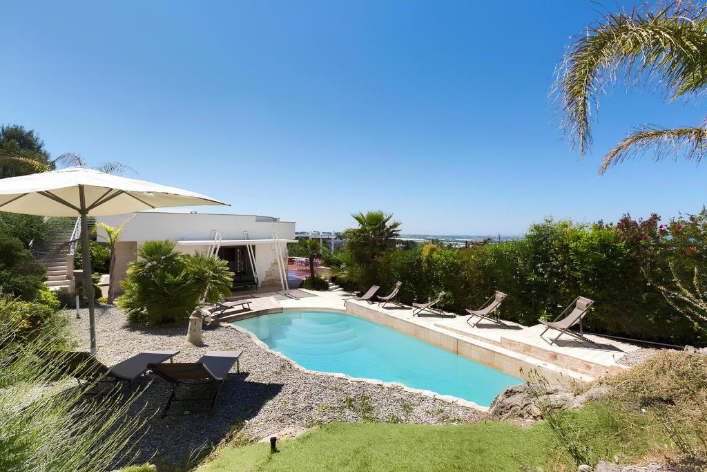 uma piscina com cadeiras e um guarda-sol em Villa Iside Luxury Stay em Conversano