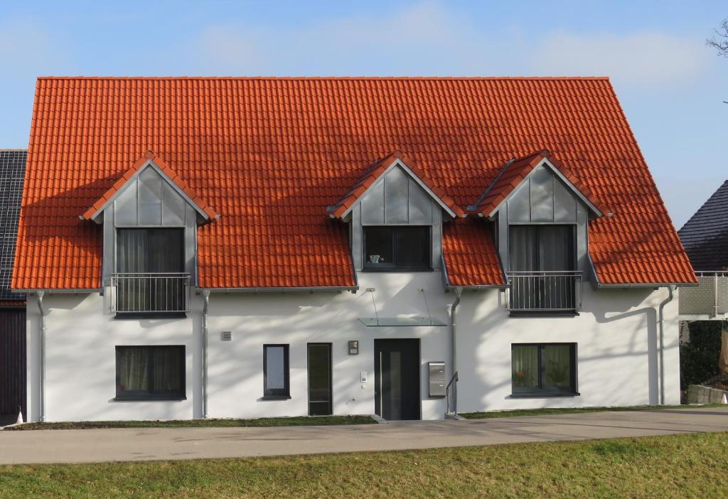 una casa blanca con techo naranja en Ferienwohnung II en Schnelldorf