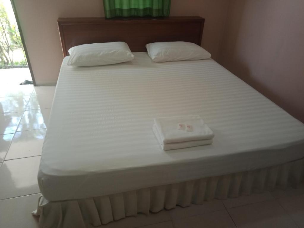 een wit bed met twee kussens erop bij เรือนแสนรัก รีสอร์ท in Ban Nong Ket Yai