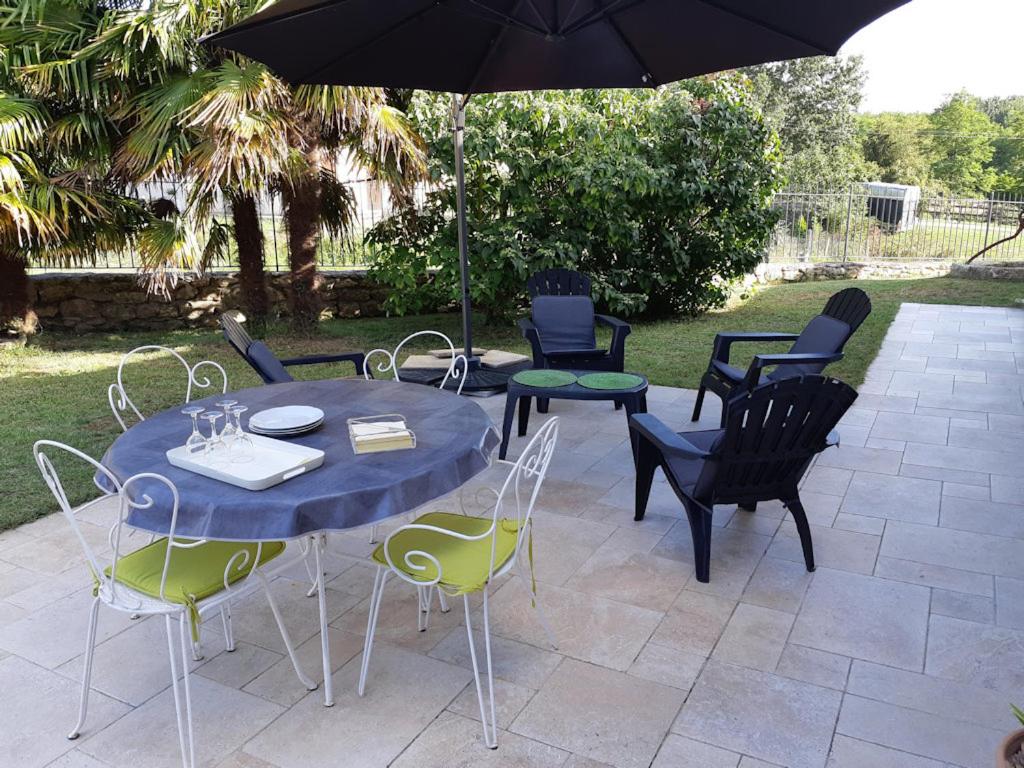 a table and chairs with an umbrella on a patio at Bastida in Saint-Macaire