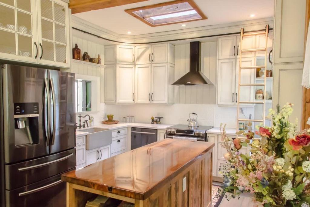 a kitchen with white cabinets and a stainless steel refrigerator at Luxury waterfront fairytale themed home - Carmen Elisabeth in Burlington