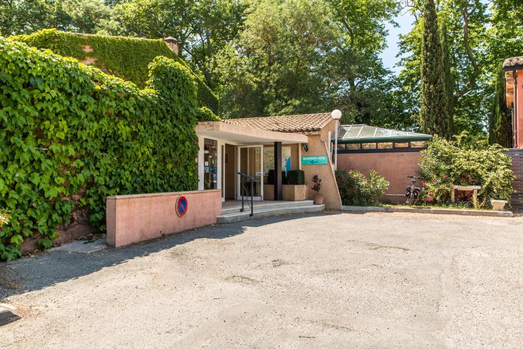 una casa con un gran seto verde en Hôtel du Canal, en Castelnaudary