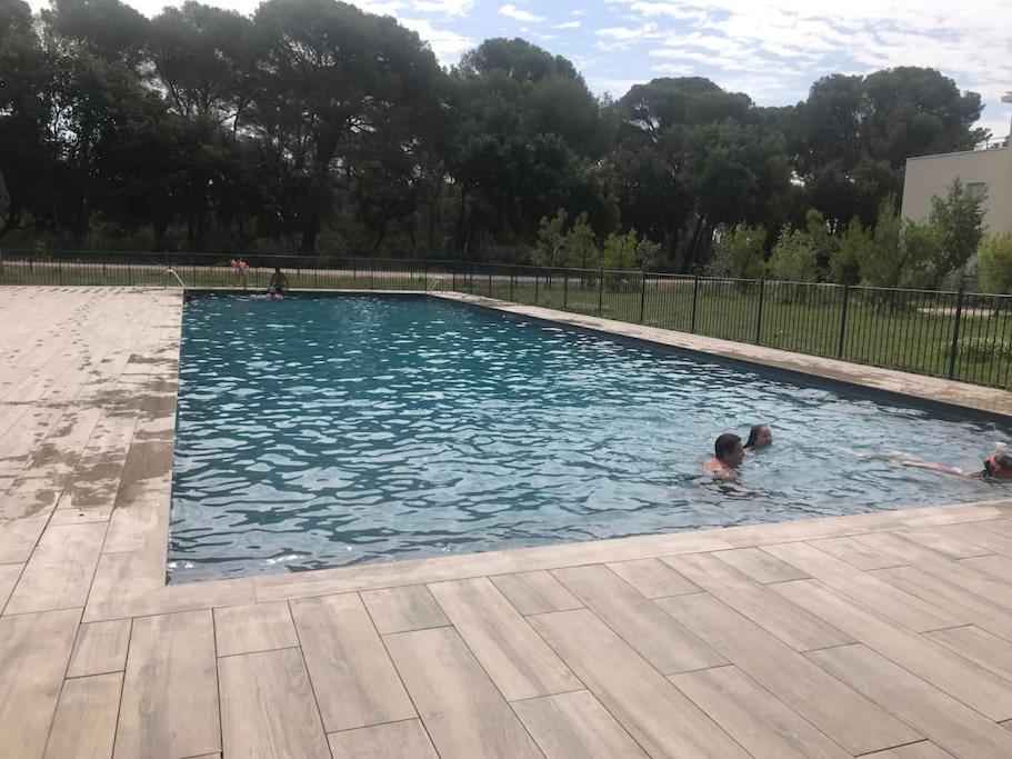 - 2 enfants dans une grande piscine dans l'établissement Appartement neuf, climatisé, piscine, terrasse, à La Londe-les-Maures