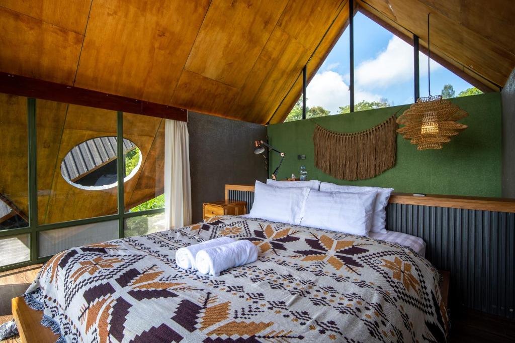 a bedroom with a bed in a room with windows at Black Wood Cabin in Kintamani