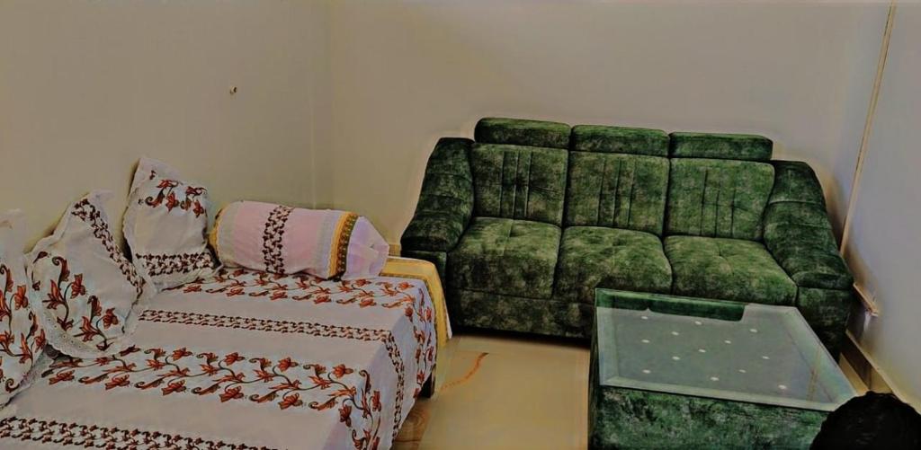 a living room with a green couch and a chair at Glamour Palace in Bodh Gaya