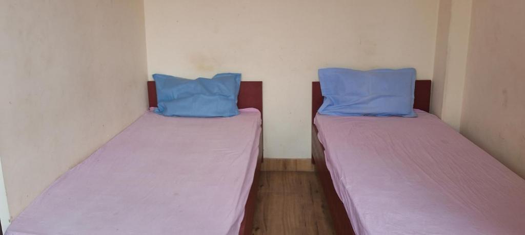 Duas camas num pequeno quarto com almofadas azuis em Sharma atithi bhavan em Prayagraj