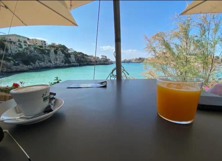 un bicchiere di succo d'arancia seduto sopra un tavolo di Houpla Porto Cristo a Porto Cristo