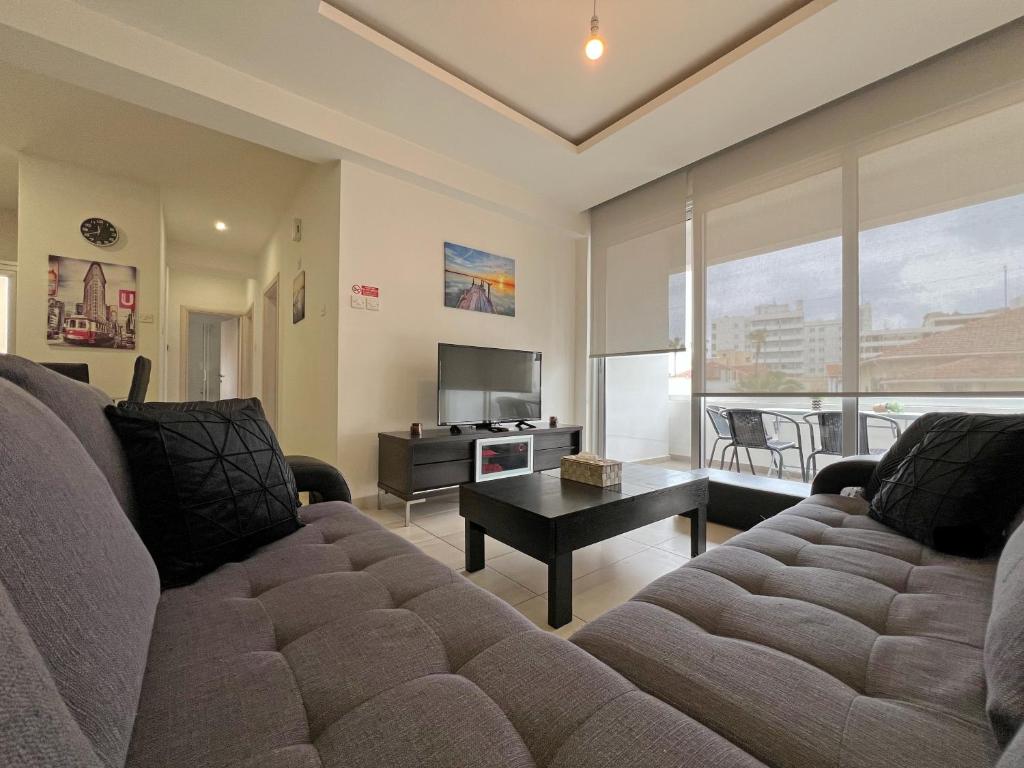 a living room with a couch and a tv at Albert's Apartment Center 202B in Larnaca