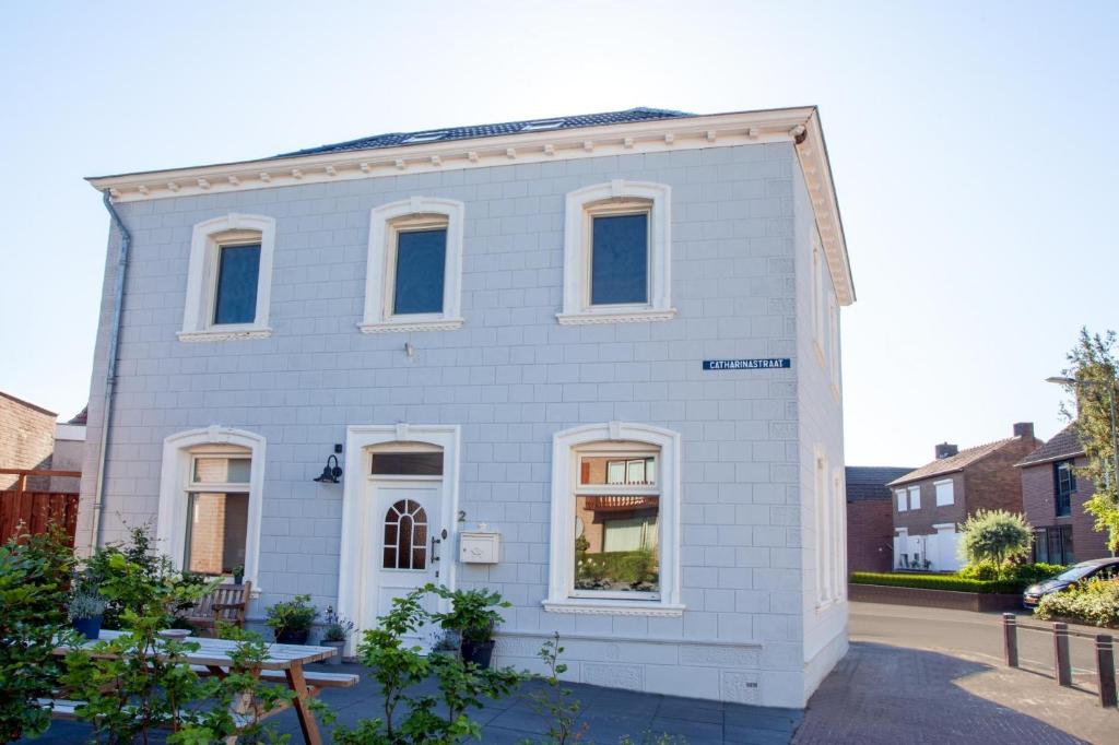 une maison blanche avec des fenêtres blanches sur une rue dans l'établissement Stijlvolle @ luxe vrijstaande woning Maastricht, à Eijsden