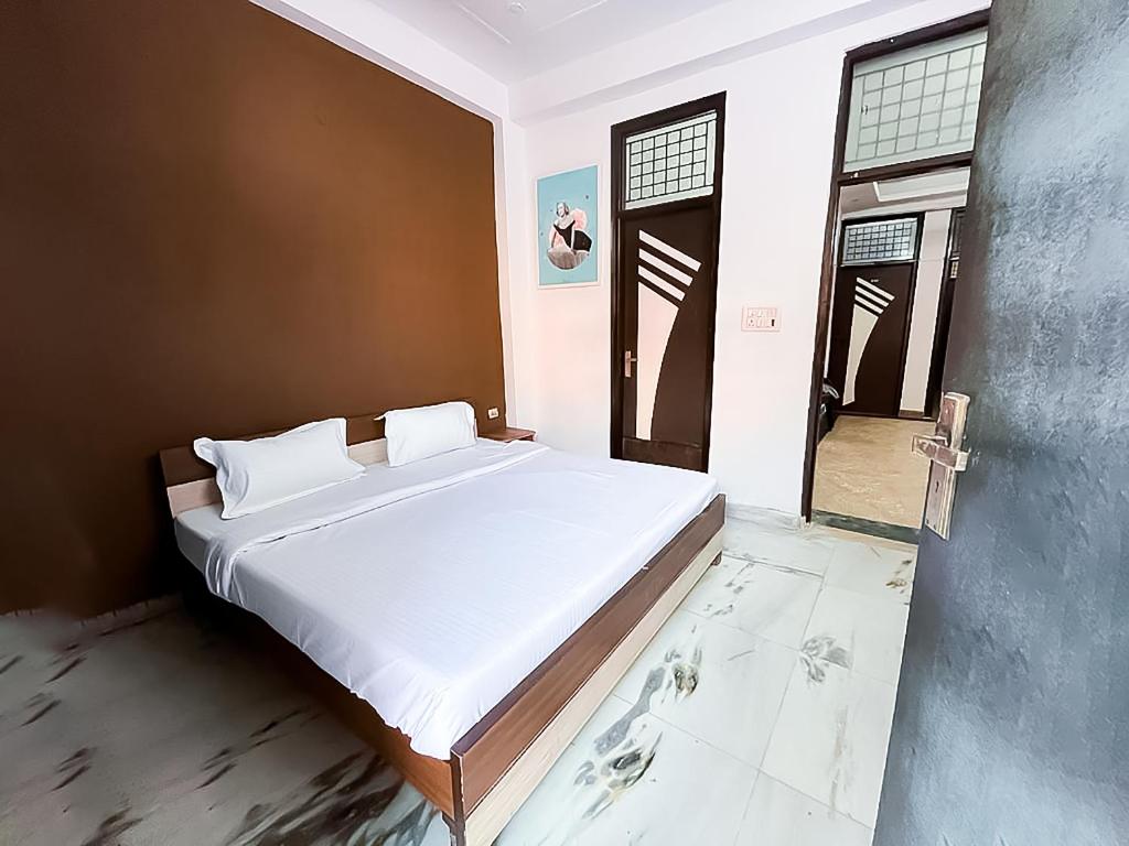 1 dormitorio con 1 cama grande con sábanas blancas en Hotel Satguru Indrapuram, Shaktikhand, en Ghaziabad