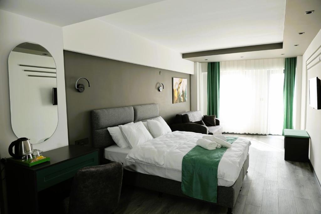 Habitación de hotel con cama y silla en Aybek Ratio Hotel en Çanakkale