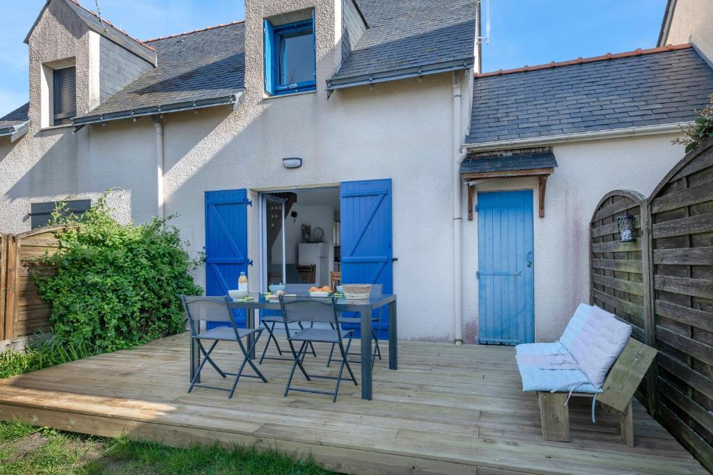 d'une terrasse avec des portes bleues, une table et des chaises. dans l'établissement Détente et repos en famille à Piriac-sur-Mer, à Piriac-sur-Mer