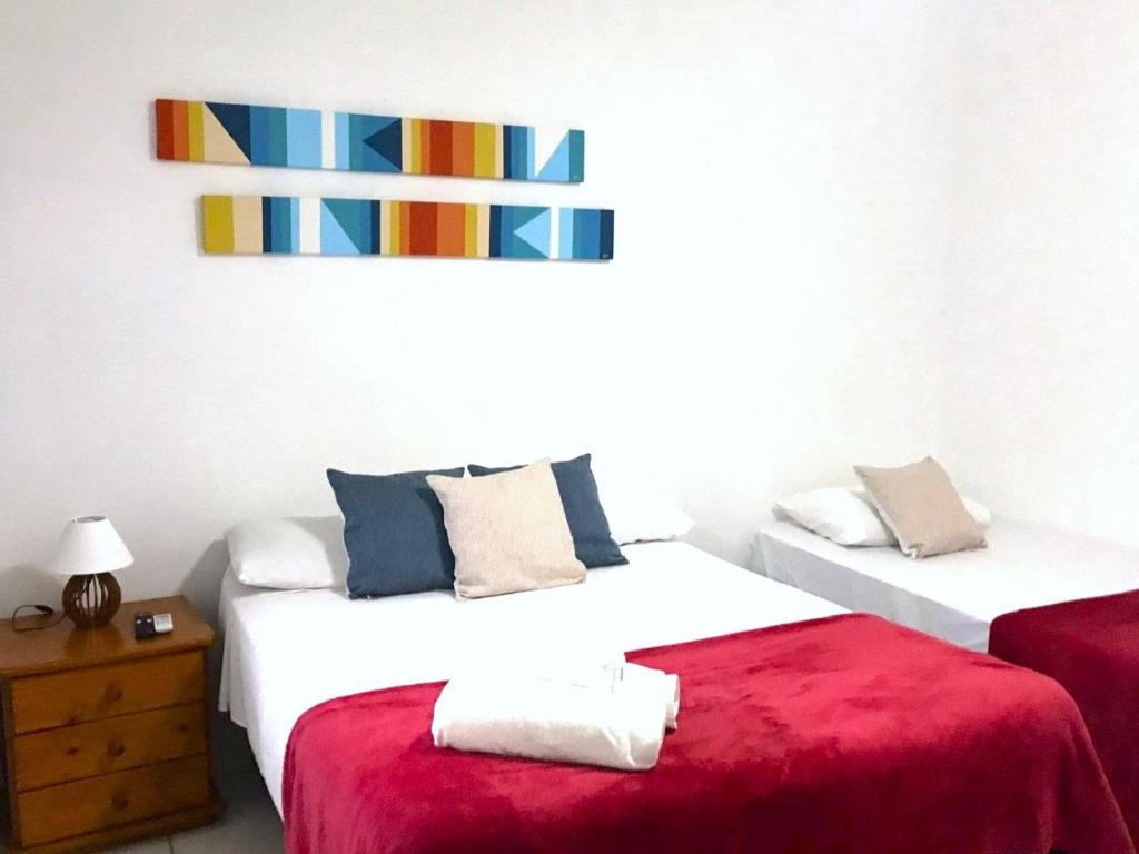 a bedroom with two beds and a painting on the wall at Suites Brothers Centro in Búzios