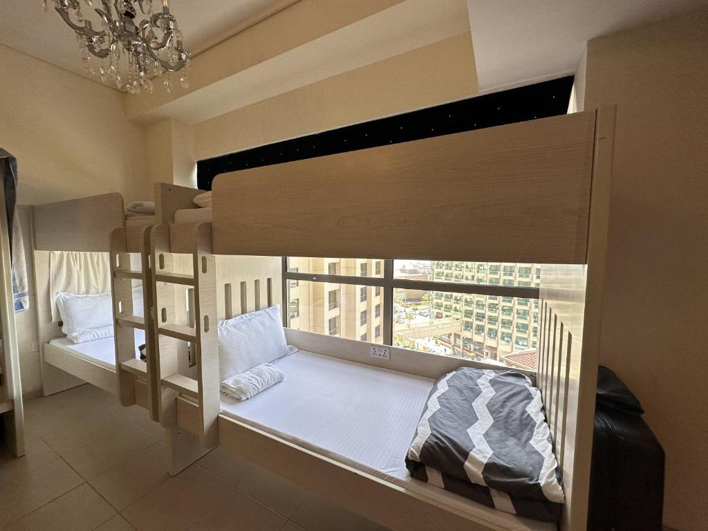 a room with two bunk beds with a window at Bollywood Beach Hostel in Dubai
