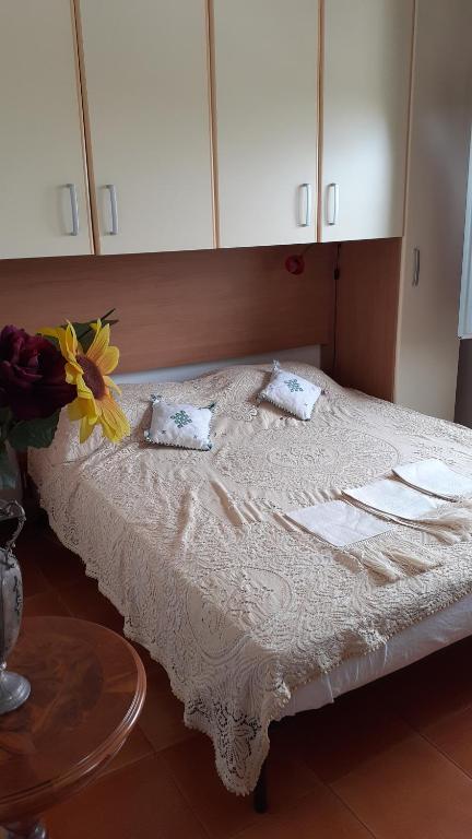 łóżko z dwoma poduszkami i wazonem kwiatów w obiekcie Affittacamere Tortolì w mieście Tortolì