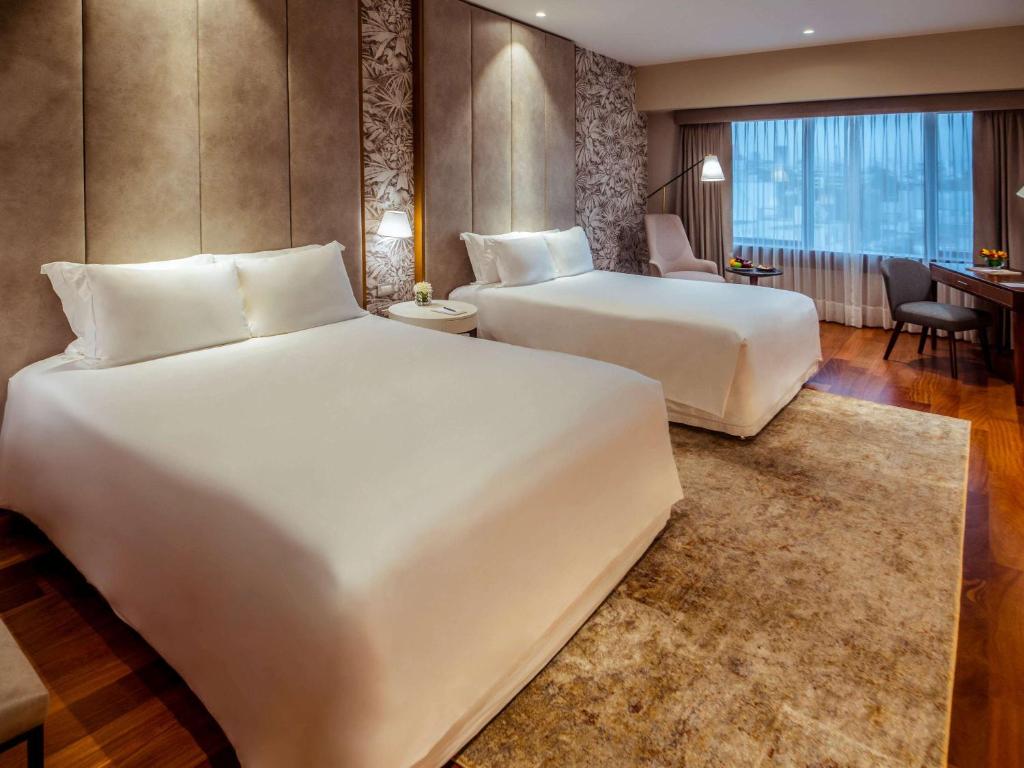 una camera d'albergo con due letti e una scrivania di Manto Hotel Lima - MGallery Collection a Lima