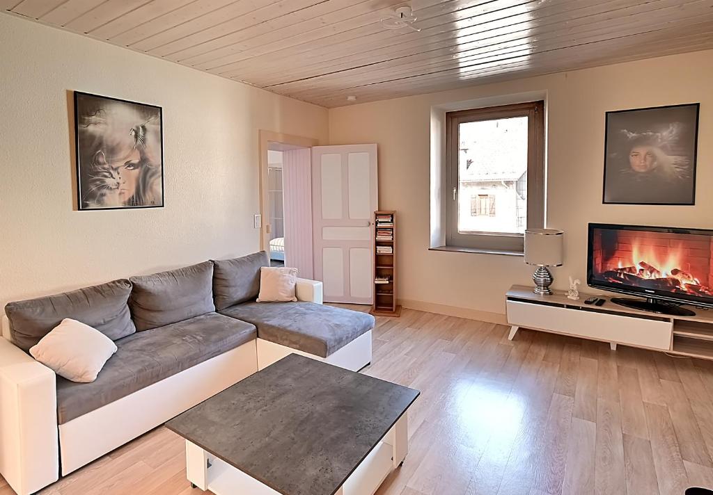 un salon avec un canapé et une télévision dans l'établissement Le Cornimont - Appartement avec vue montagne, à Cornimont