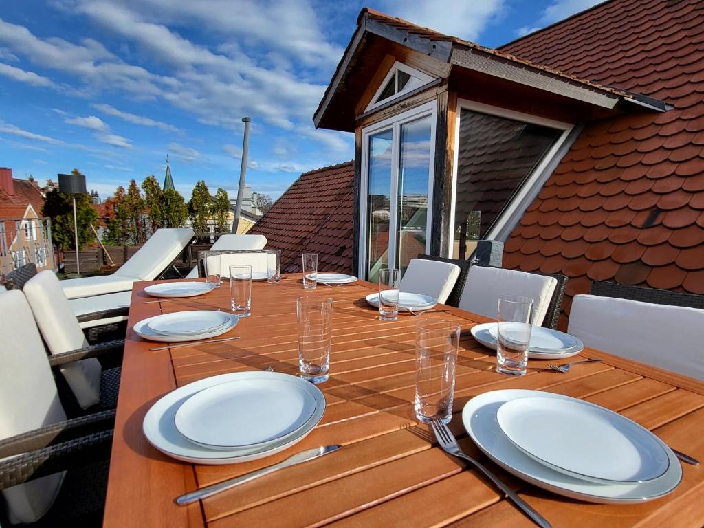 een houten tafel met borden en glazen op een balkon bij SiOUX: luxuriöse Penthousewohnung im Stadtzentrum in Kempten