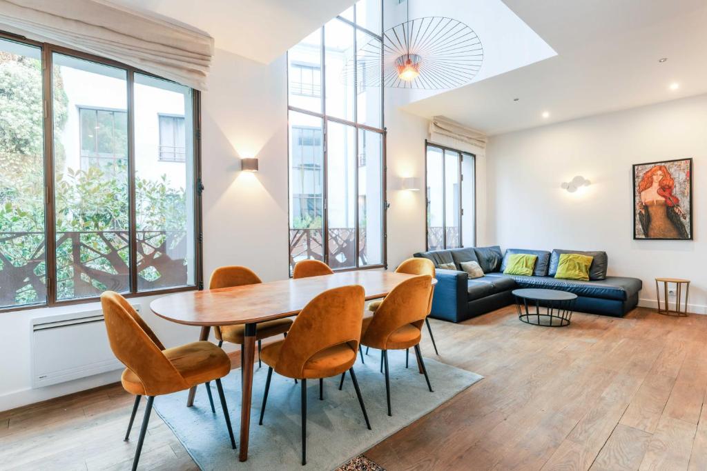 un salon avec une table, des chaises et un canapé dans l'établissement Bastille - Elegant duplex loft -6P, à Paris
