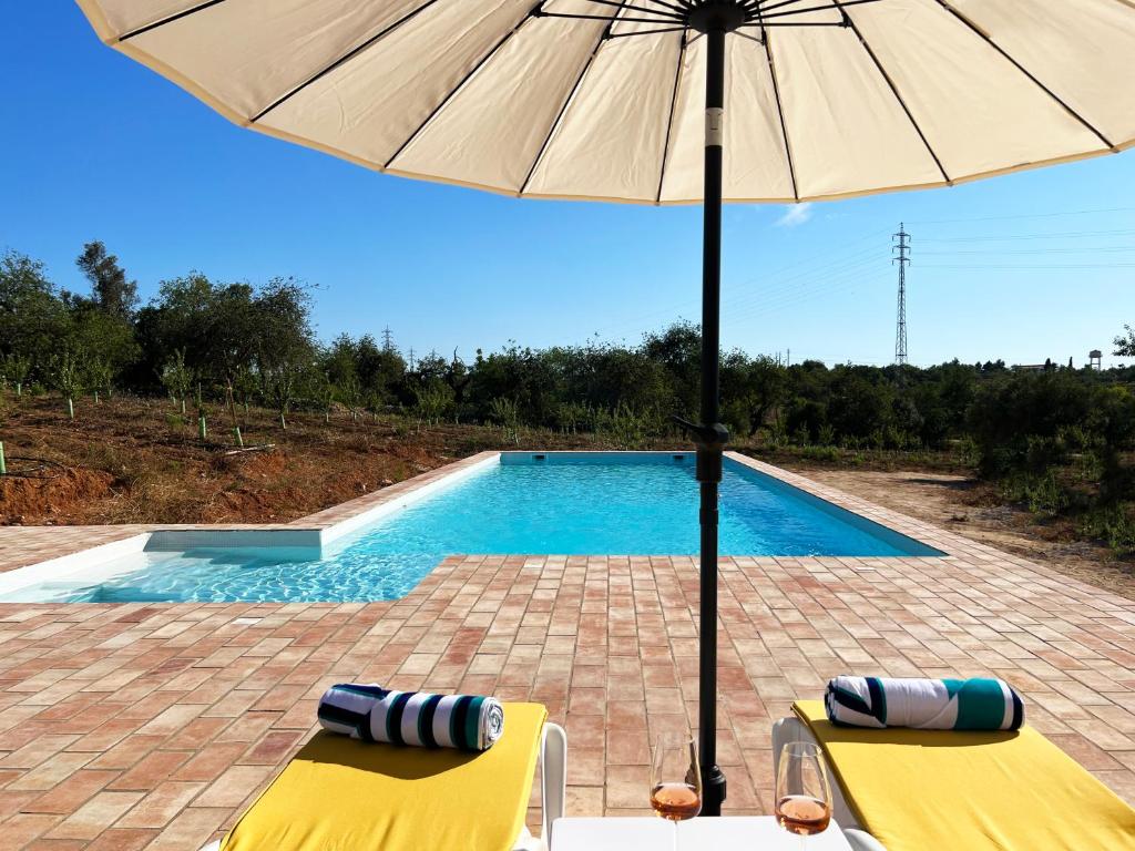 塔維拉的住宿－Monte das Açoteias - Agroturismo，一个带两把椅子和一把遮阳伞的游泳池