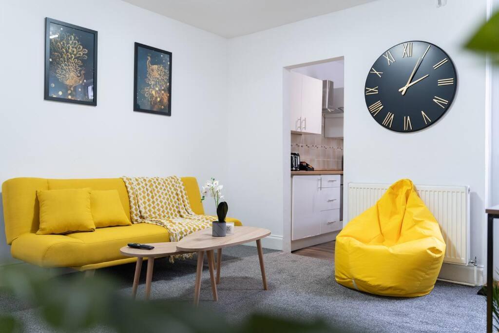 a living room with a yellow couch and a clock at Open Mind Property - Luxury House & Free Parking in Portsmouth