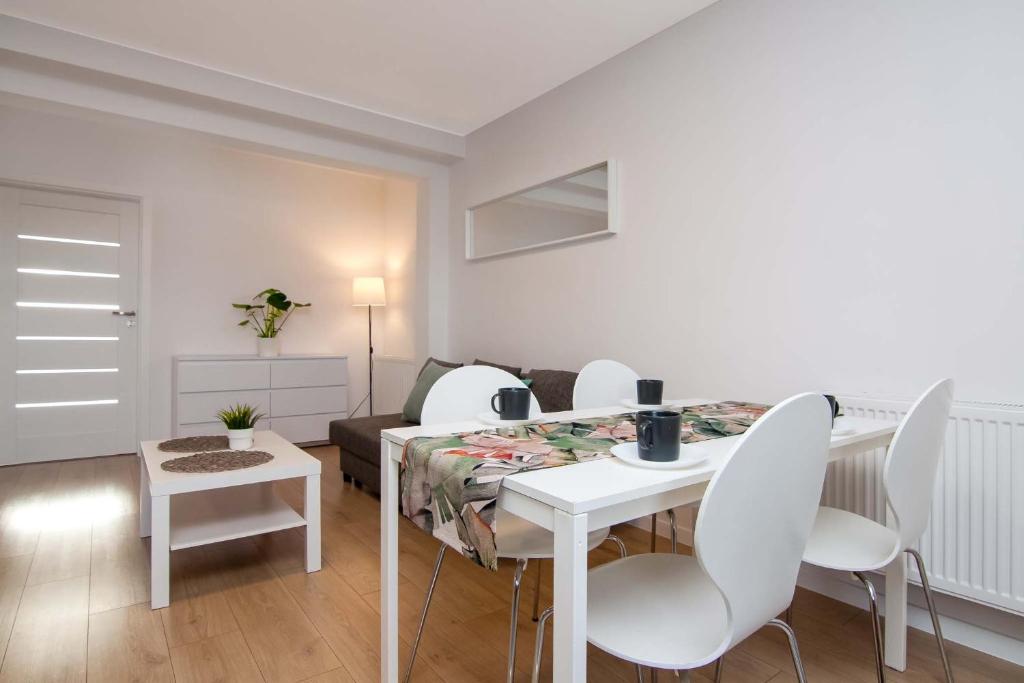 ein weißes Esszimmer mit einem Tisch und weißen Stühlen in der Unterkunft Apartament Chełm City in Chełm