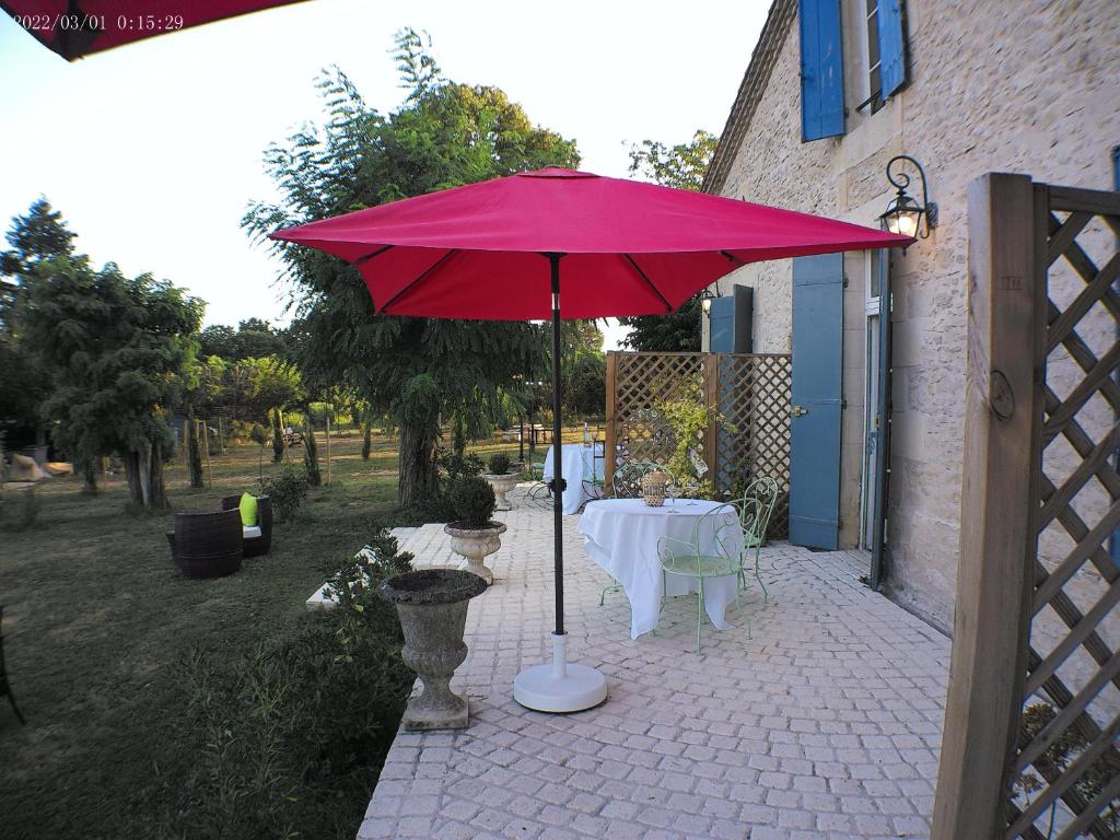 una mesa con una sombrilla roja en el patio en le mas de lombreyra, en Massugas