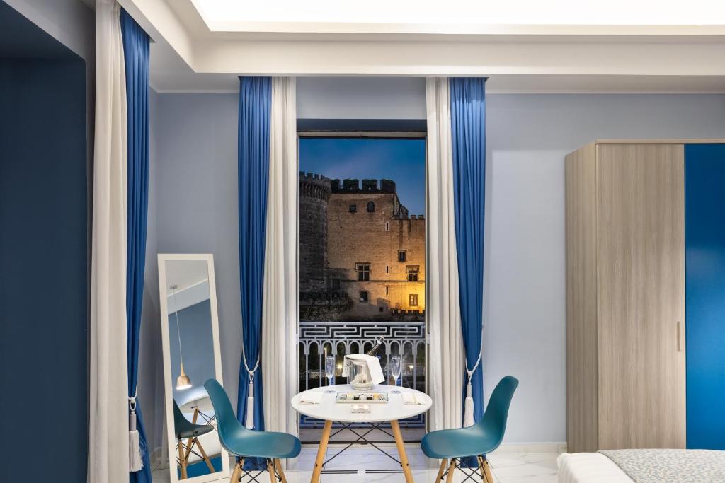 Cette chambre comprend une table et des chaises et offre une vue sur le château. dans l'établissement MAIN - Municipio, à Naples