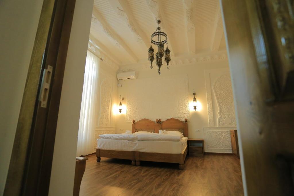 sypialnia z łóżkiem i żyrandolem w obiekcie Best Hotel Muqaddam w mieście Buchara