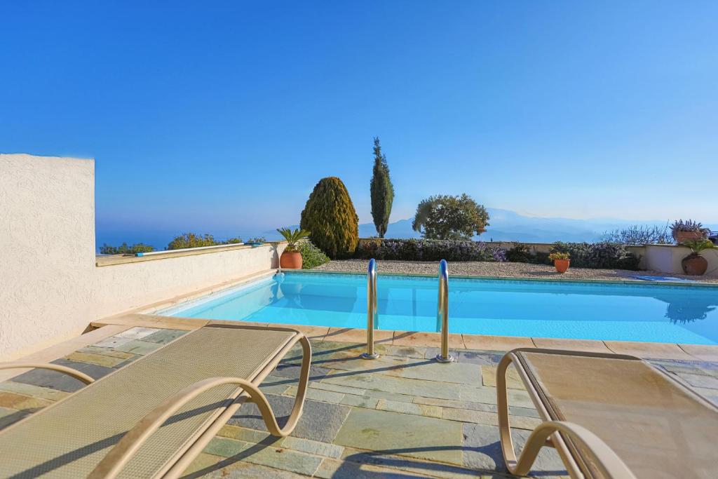 a swimming pool with two chairs in front of a house at Villa Angelena in Droushia