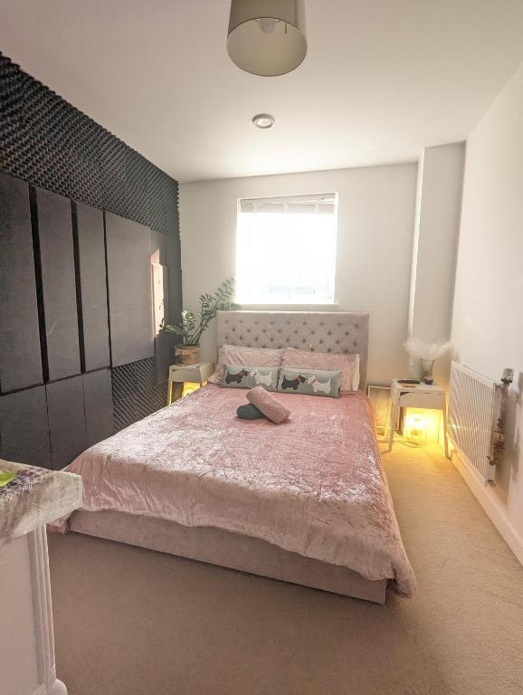 a bedroom with a large bed with a pink bedspread at Modern room with private bathroom and free parking in Goodmayes