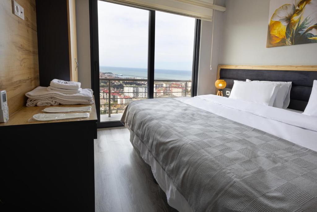ein Schlafzimmer mit einem großen Bett und einem großen Fenster in der Unterkunft ZAL SUİTE in Trabzon