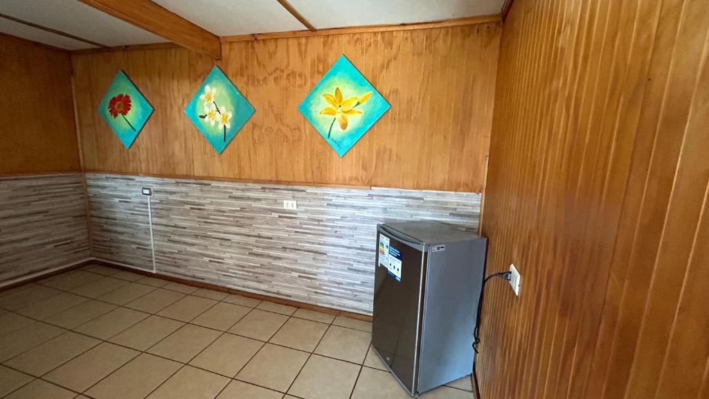 Zimmer mit Kühlschrank und Drachen an der Wand in der Unterkunft Cabañas Mahatua in Hanga Roa